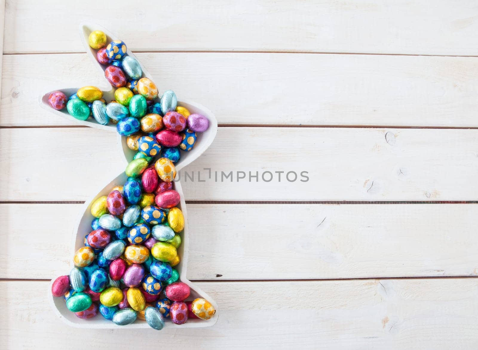 Colorful Easter eggs made of chocolate on white wood background