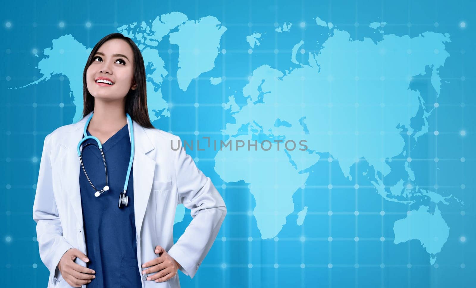 Pretty asian medical doctor with white coat looking up over blue background