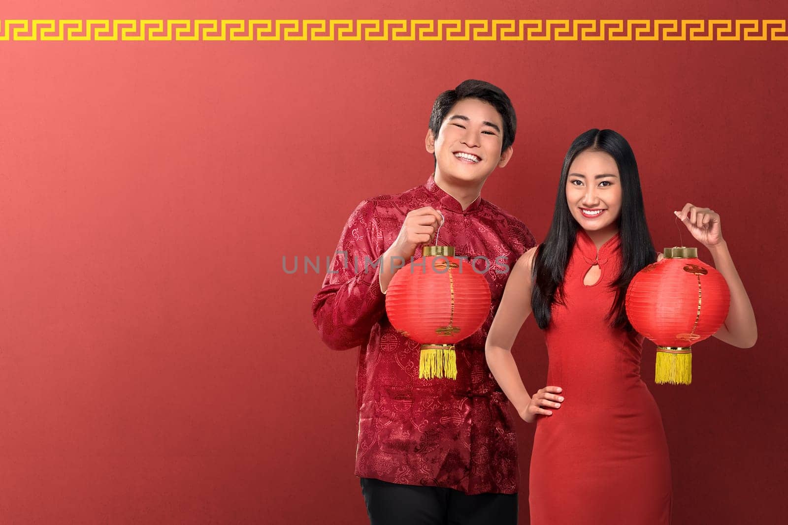 Beautiful chinese couple holding red lanterns on red background. Happy Chinese New Year