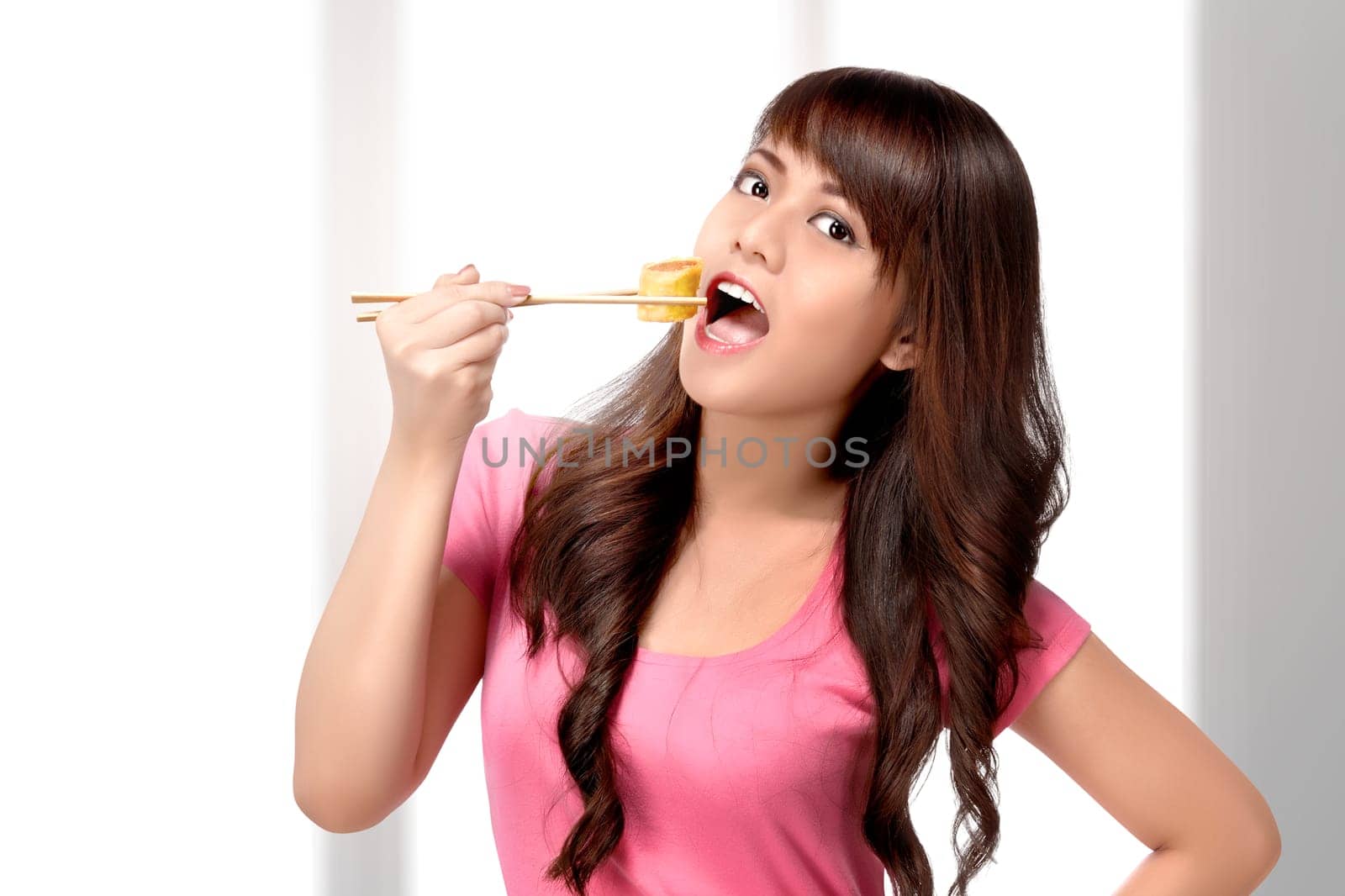 Beautiful asian woman eating sushi using chopsticks on the home