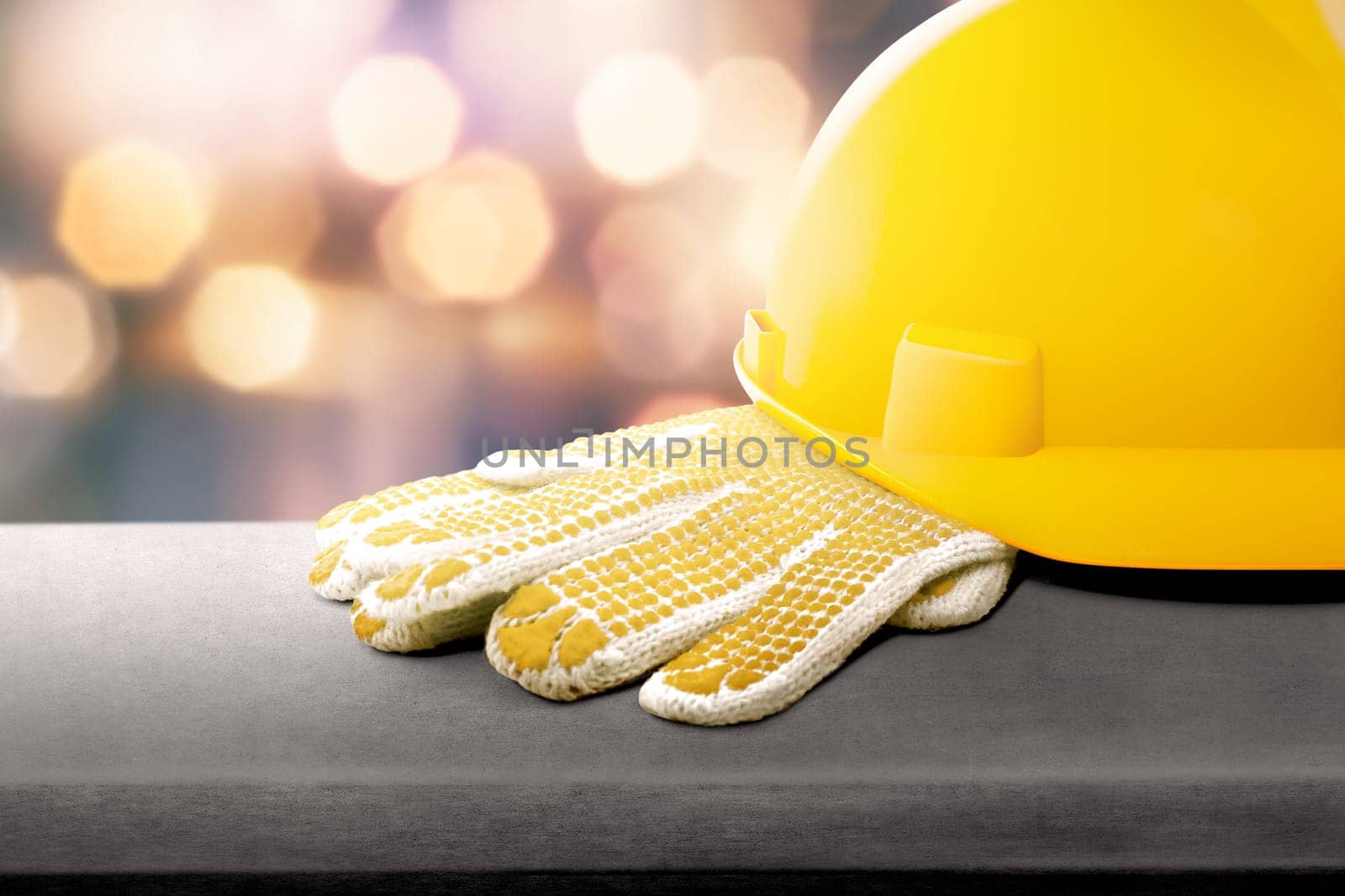 Safety helmet and gloves on the table with blur lights background