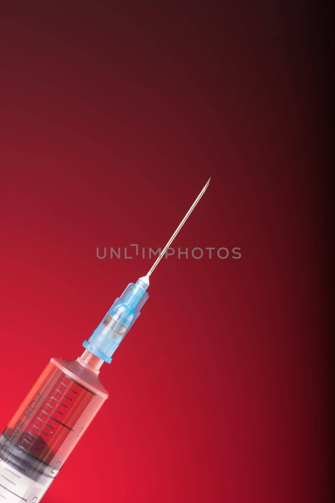 Isolated medical syringe on red, dark background