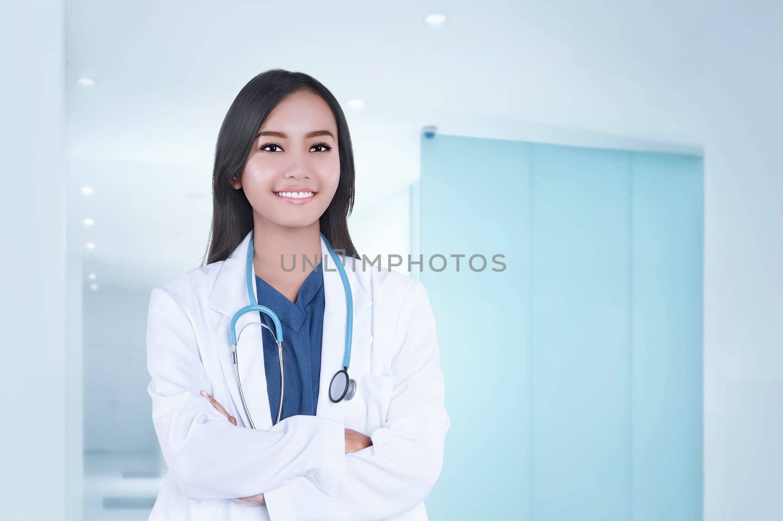 Beautiful asian doctor woman in white coat with crossed hands on clinic