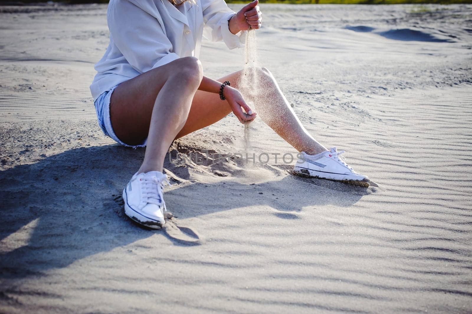 lovely young woman with curly hair, the romance of youth, a journey walk on a warm summer sunny day on a sandy beach with water