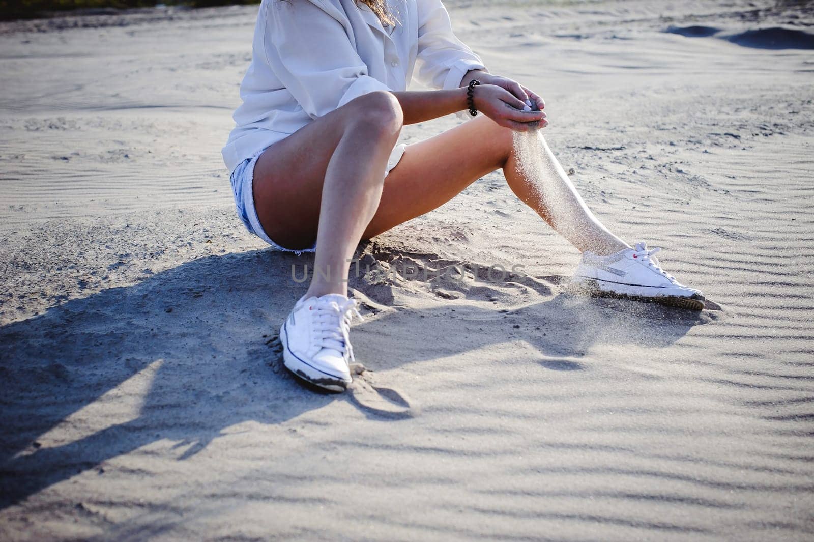lovely young woman with curly hair, the romance of youth, a journey walk on a warm summer sunny day on a sandy beach with water