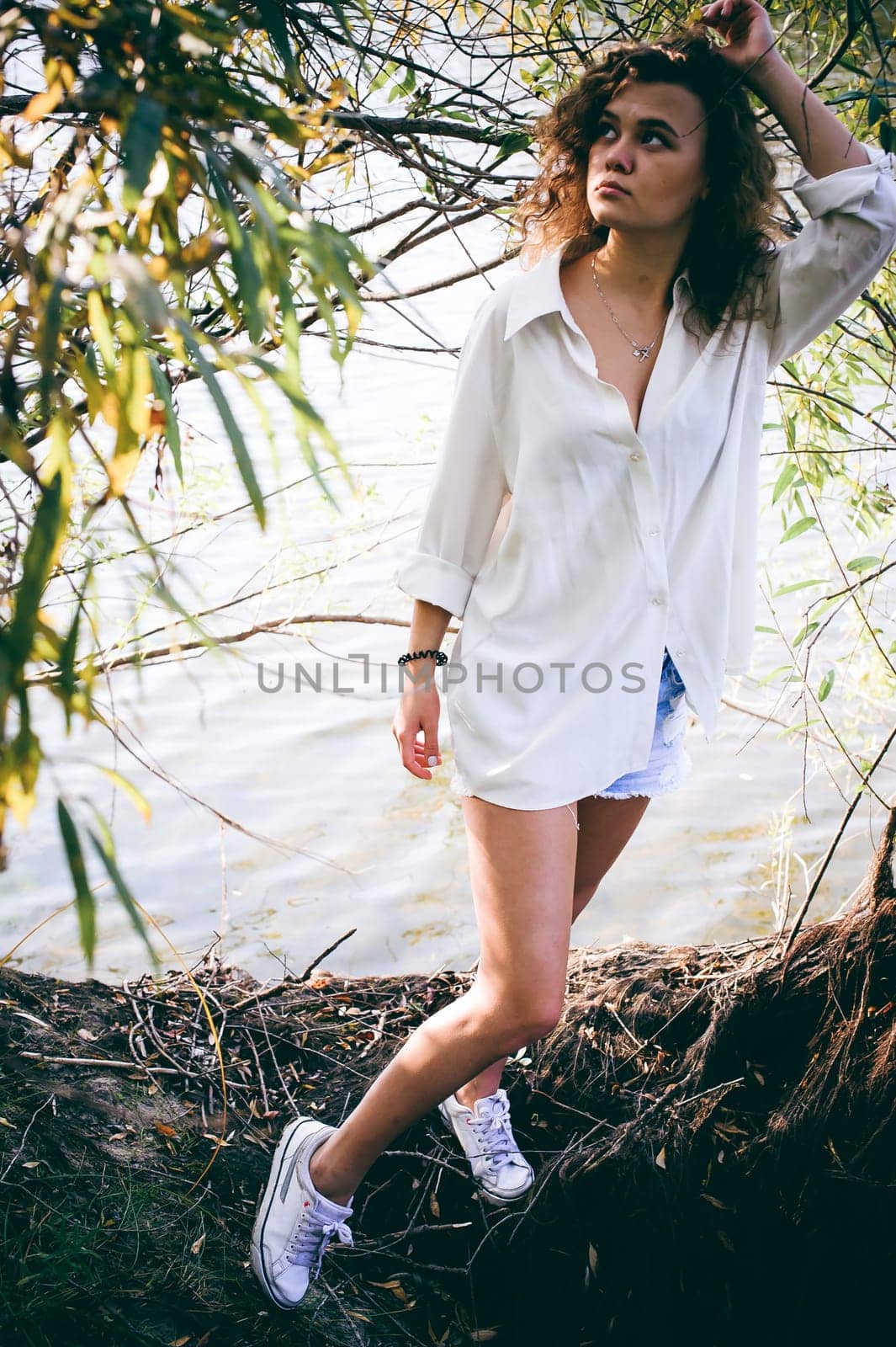 lovely young woman with curly hair, the romance of youth, a journey walk on a warm summer sunny day on a sandy beach with water