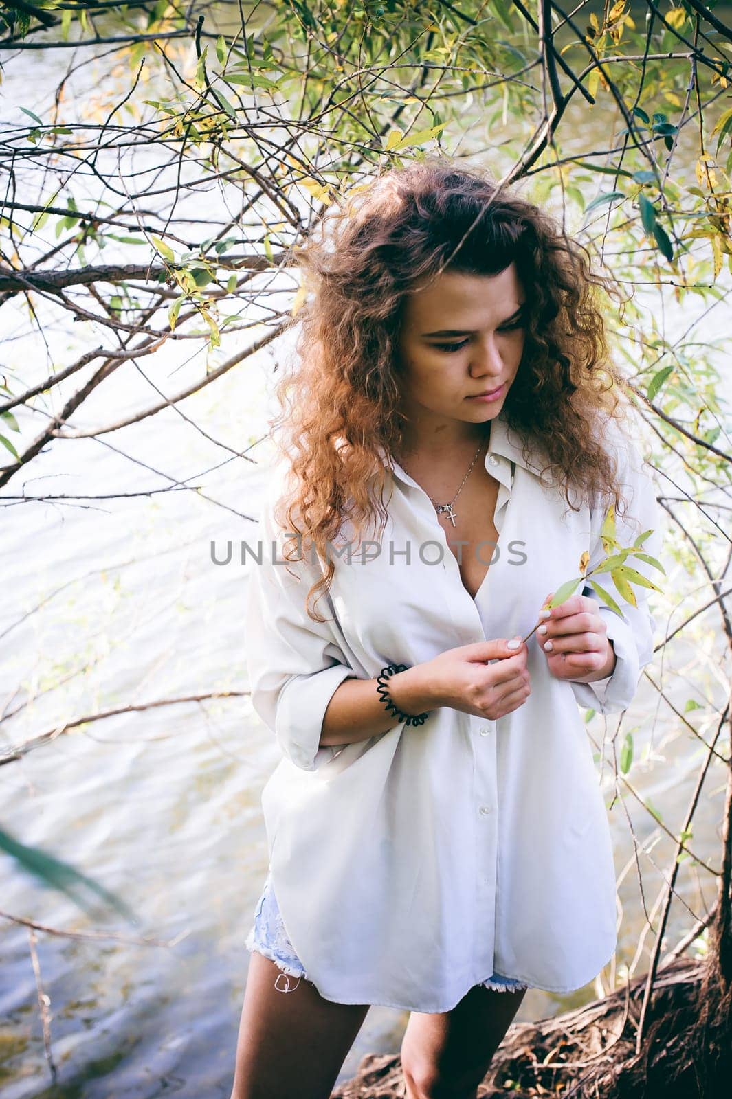 lovely young woman with curly hair, the romance of youth, a journey walk on a warm summer sunny day on a sandy beach with water