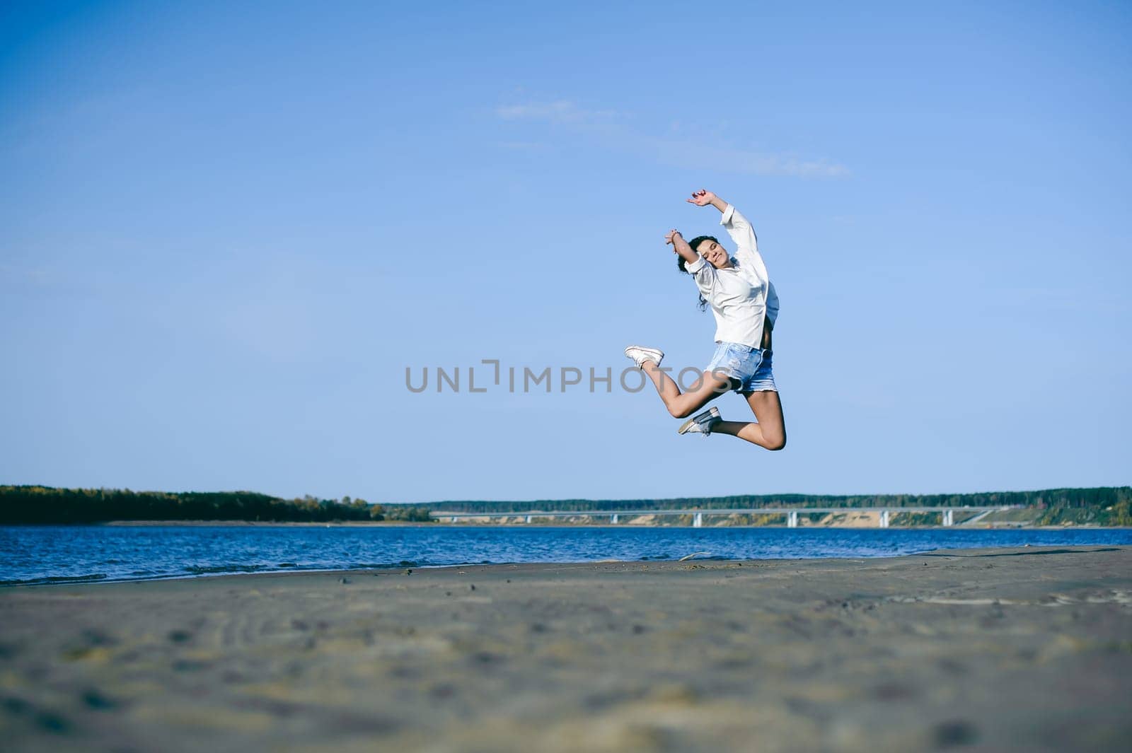 lovely young woman with curly hair, the romance of youth, a journey walk on a warm summer sunny day on a sandy beach with water