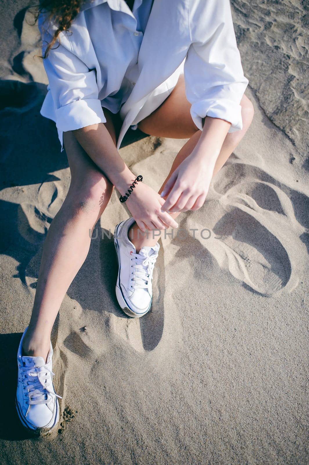lovely young woman with curly hair, the romance of youth, a journey walk on a warm summer sunny day on a sandy beach with water