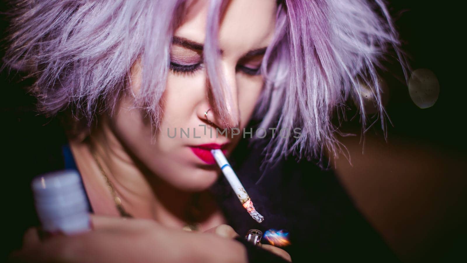 Portrait of a girl with a cigarette. young beautiful girl hipster smoking a cigarette in the street under the snow. her hands lights a lighter, lighting a cigarette tobacco