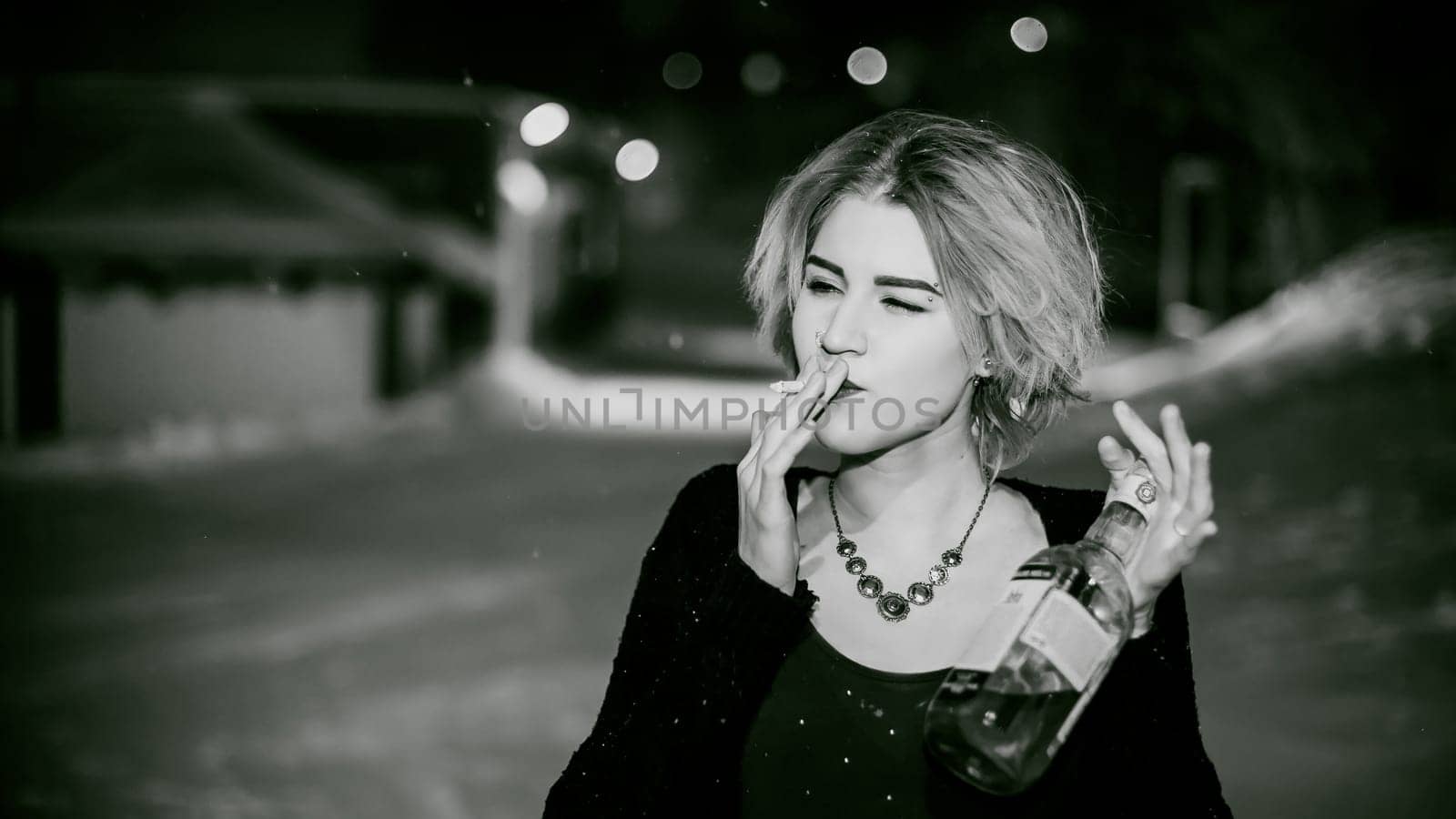 Black and white portrait of a girl with a cigarette. young beautiful woman with dyed hair smoking a cigarette in the street under the snow