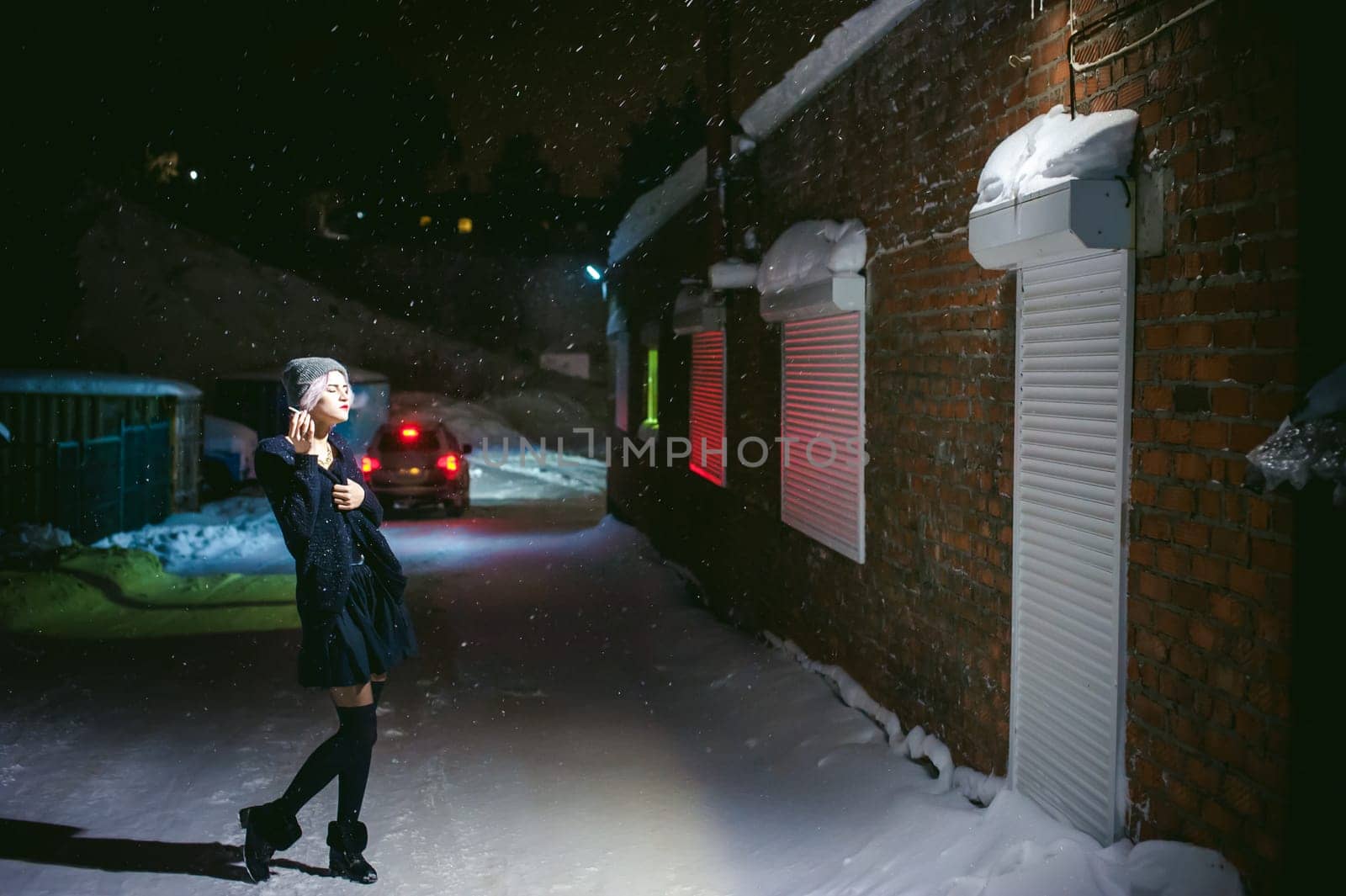 Portrait of a girl with a cigarette. young beautiful girl with dyed hair hipster hat. cigarette smoking on the street under the snow