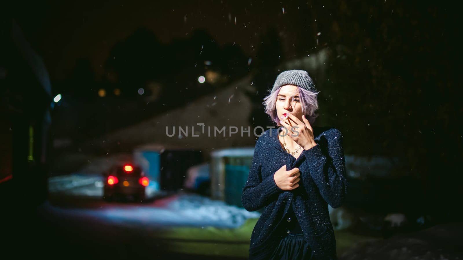 Portrait of a girl with a cigarette. young beautiful girl with dyed hair hipster hat. cigarette smoking on the street under the snow
