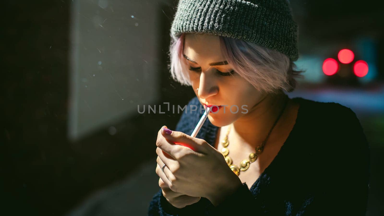 Portrait of a girl with a cigarette. young beautiful girl hipster with dyed hair smoking a cigarette in the street under the snow. her hands lights a lighter, lighting a cigarette tobacco