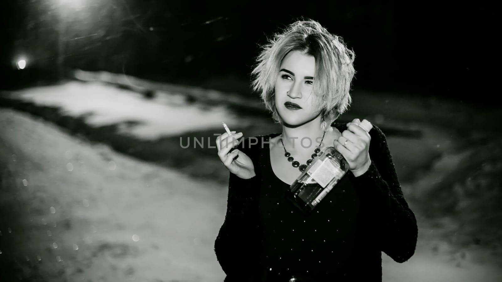 Black and white portrait of a girl with a cigarette. young beautiful woman with dyed hair smoking a cigarette in the street under the snow