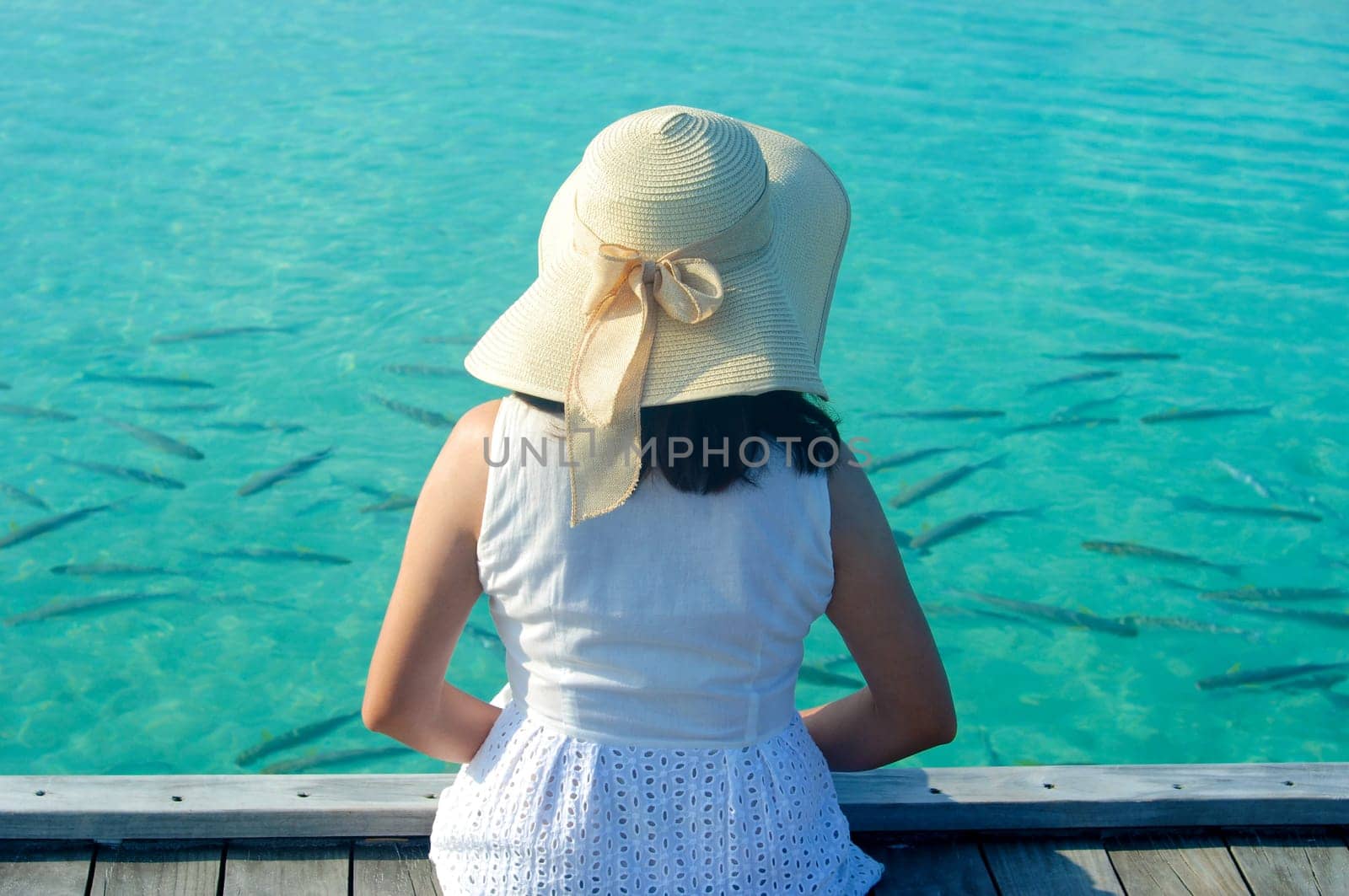 Beautiful asian woman in sunhat sitting and  relaxed at tropical beach in Maldives