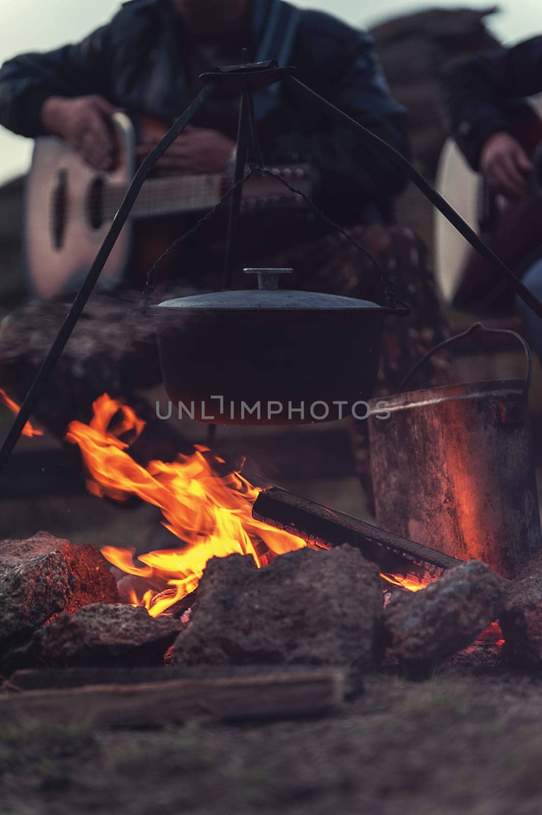 Closeup photo of the man playing o guitar near the campfire