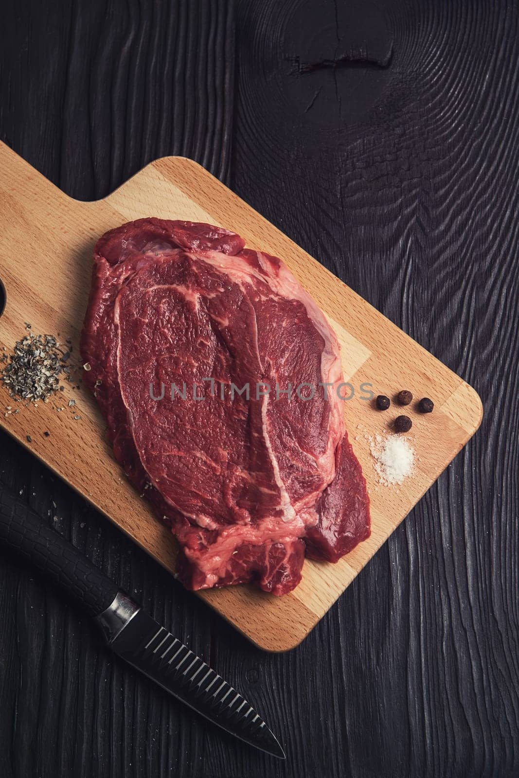 Fresh raw beef meat steaks in the black plate with spices on black wooden background