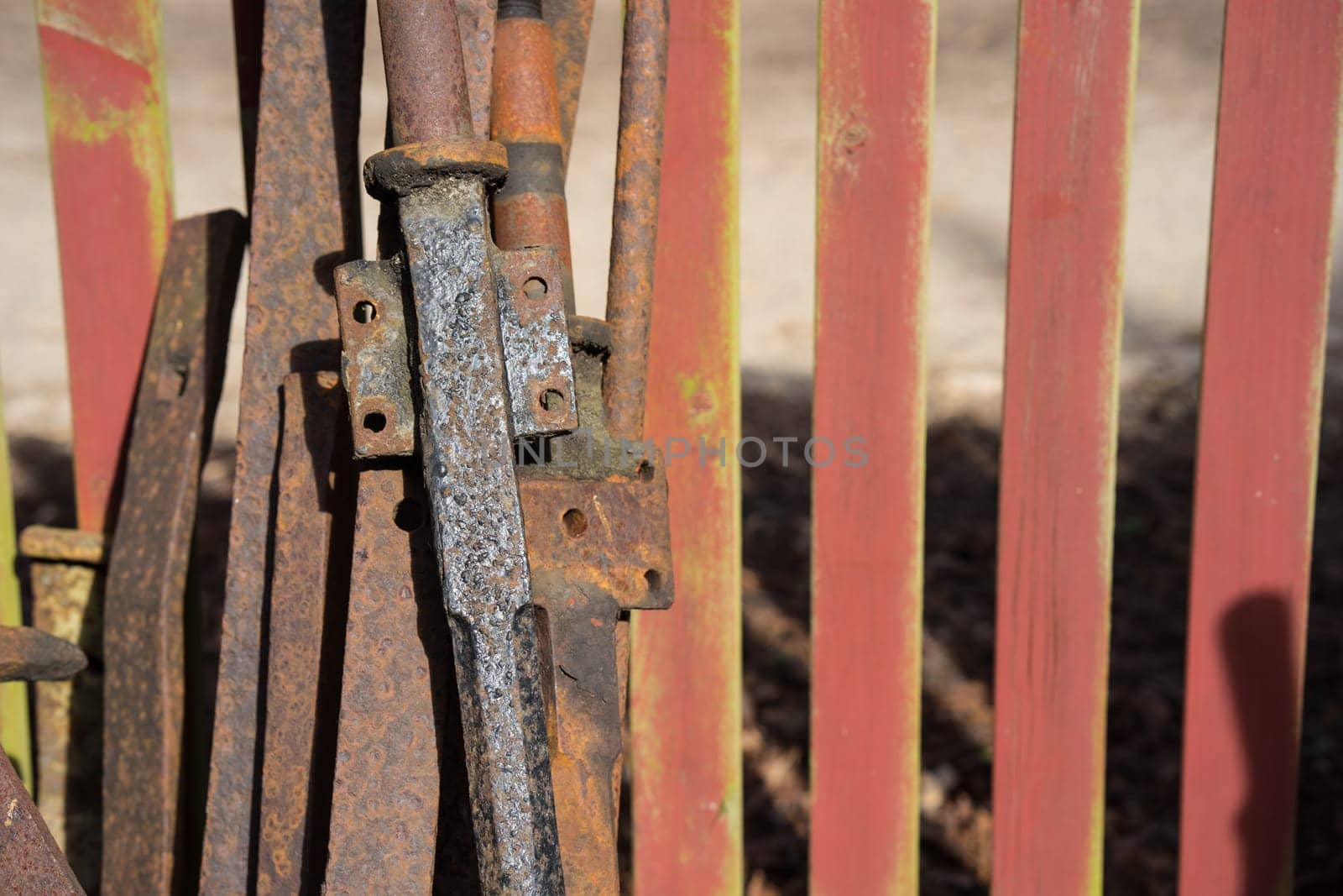 rusted iron leaning out of red painted stakit