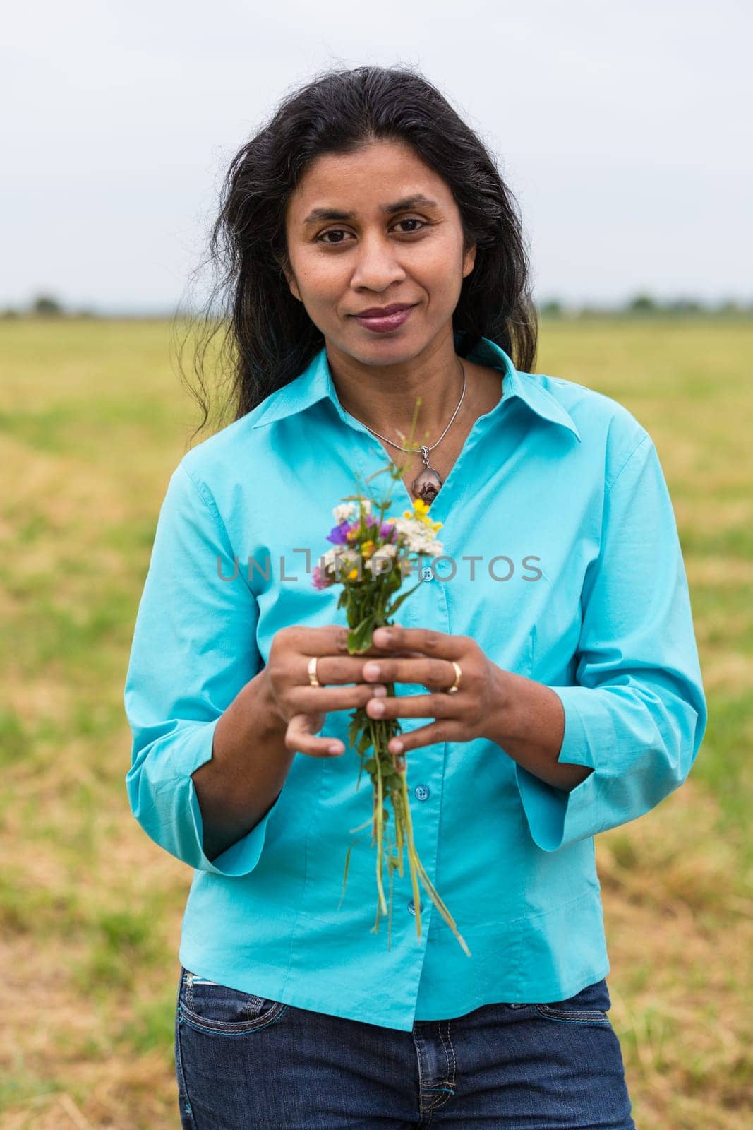 Attractive woman with self-picked flowers on summer meadow