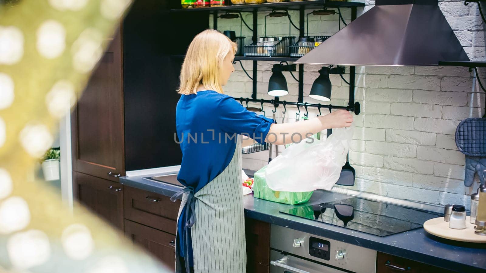 woman with shopping bags parses the kitchen. housewife in apron in the kitchen arranges bought food