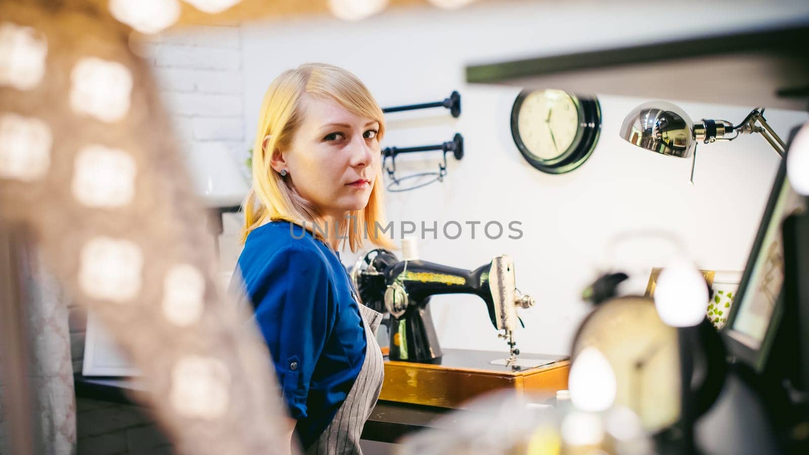 seamstress work on the sewing machine. young blonde woman working on a mechanical sewing machine at home sitting at your desk, be prepared to sew