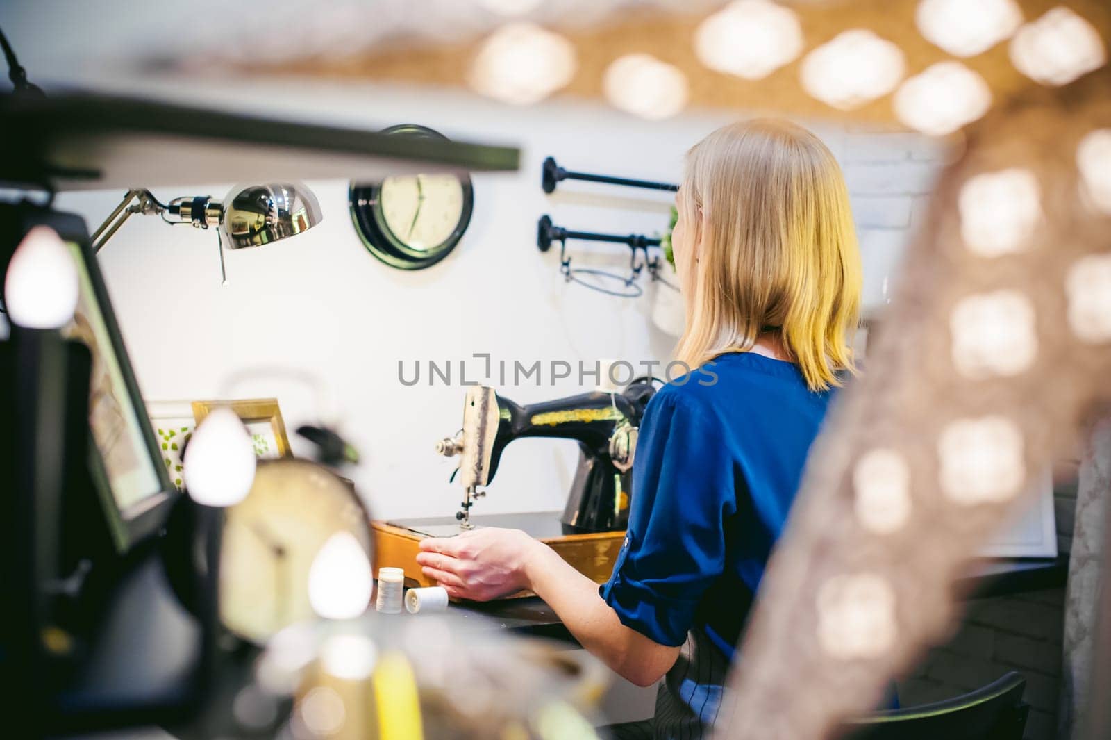 seamstress work on the sewing machine. young blonde woman working on a mechanical sewing machine at home sitting at your desk, be prepared to sew