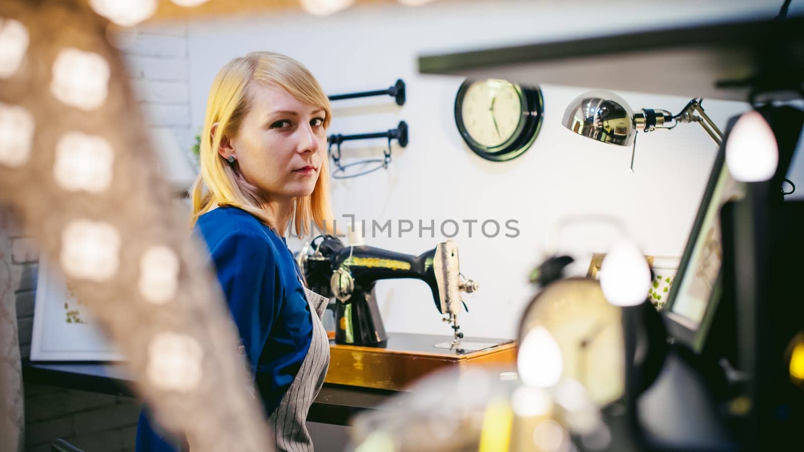 seamstress work on the sewing machine. young blonde woman working on a mechanical sewing machine at home sitting at your desk, be prepared to sew