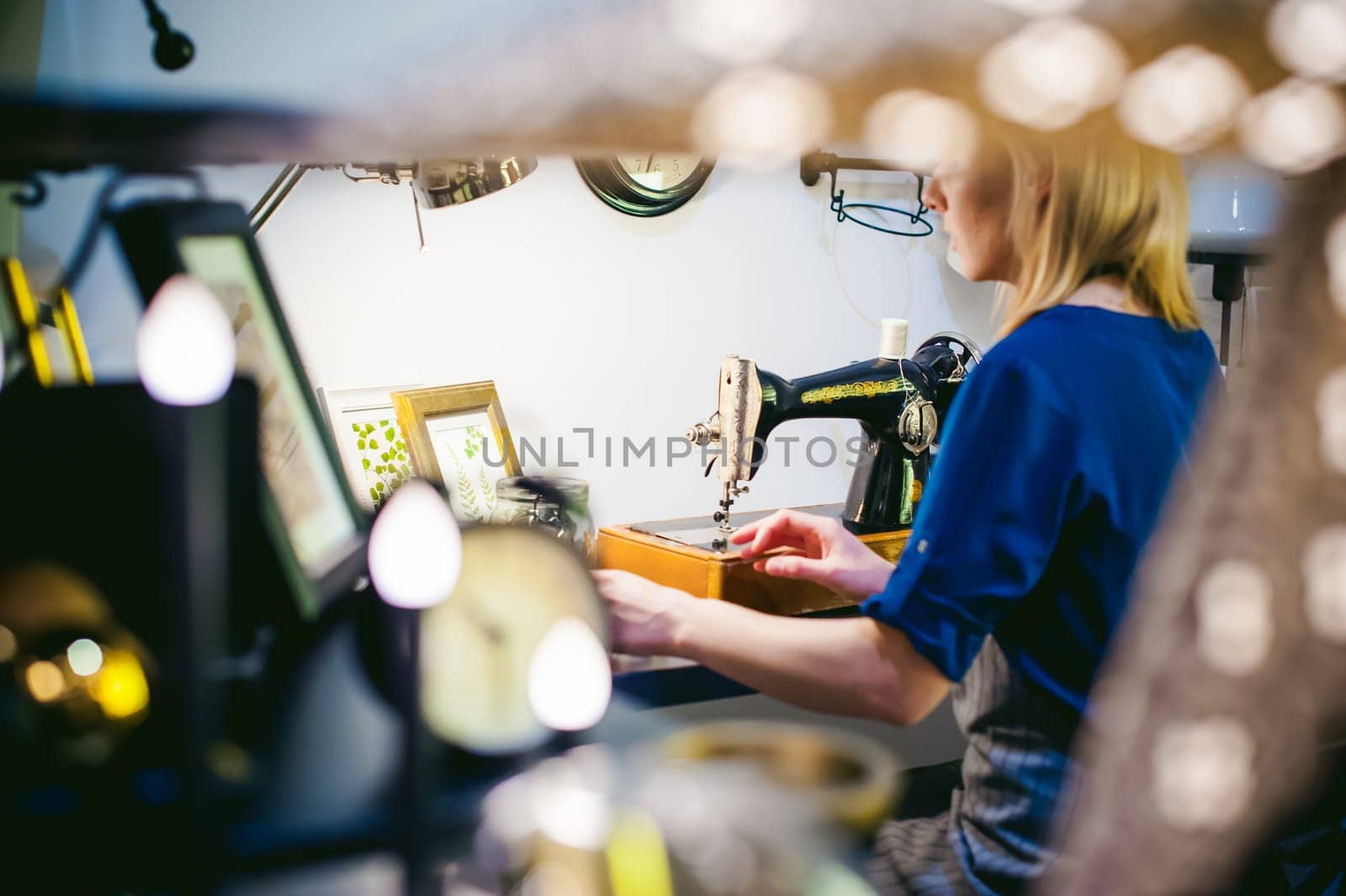 seamstress work on the sewing machine. young blonde woman working on a mechanical sewing machine at home sitting at your desk, be prepared to sew