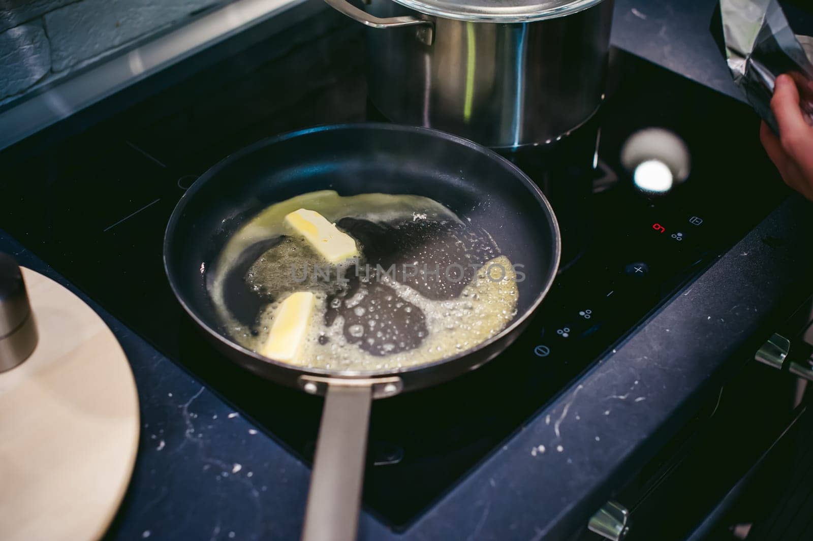 woman housewife prepares fried eggs with ham and vegetables in his kitchen. spreads the butter in the pan