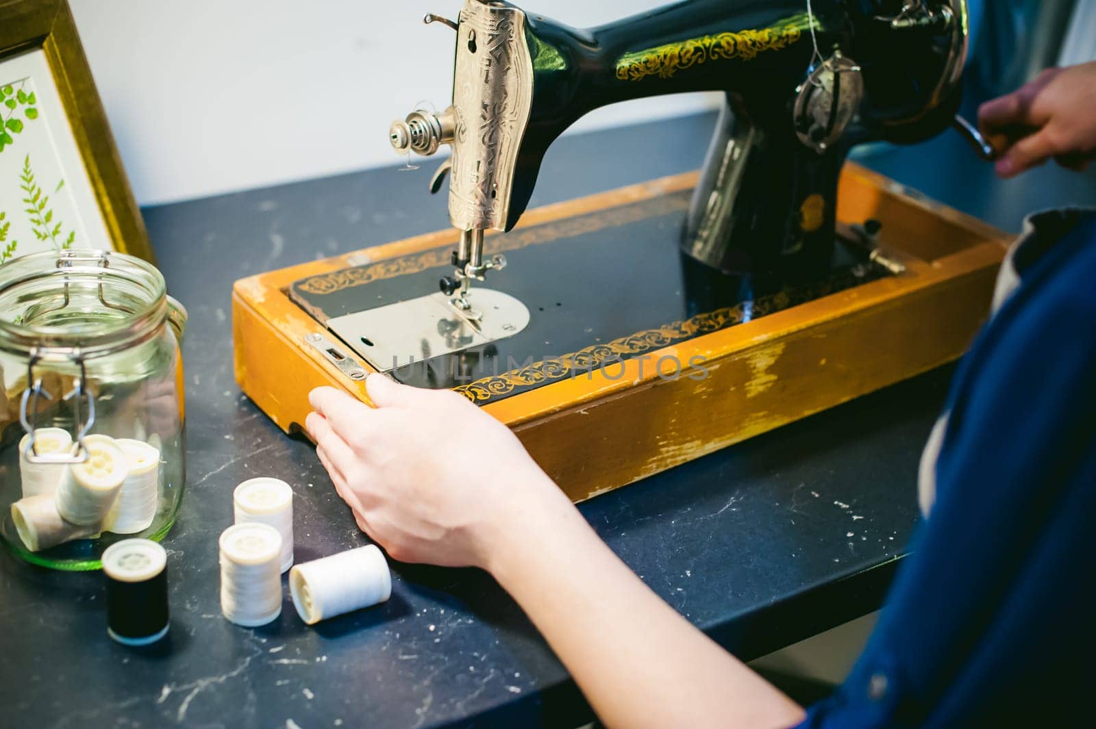 Hands seamstress work on the sewing machine. young blond woman working on a mechanical sewing machine at home sitting at your desk, be prepared to sew