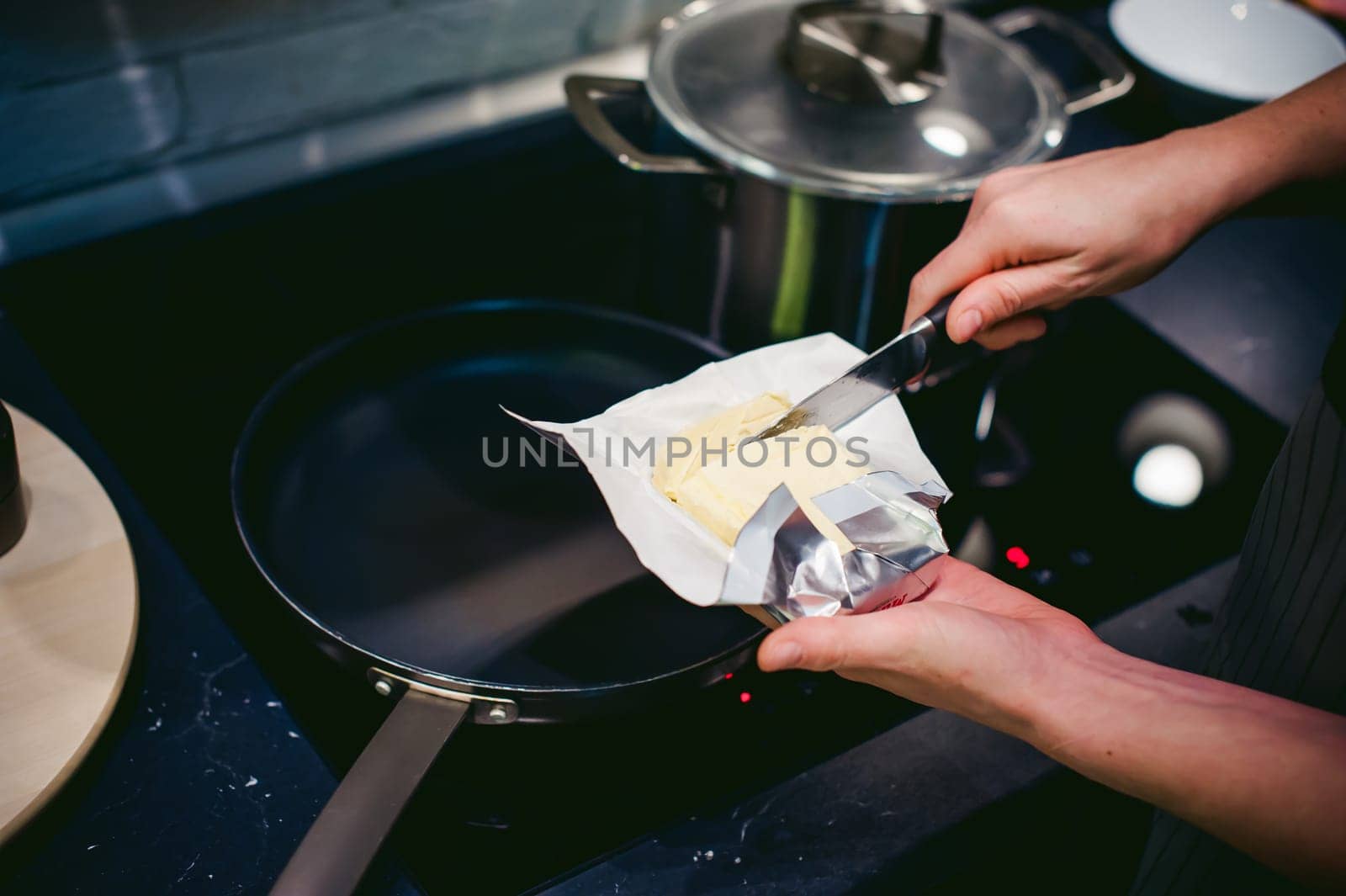 woman housewife prepares fried eggs with ham and vegetables in his kitchen. spreads the butter in the pan