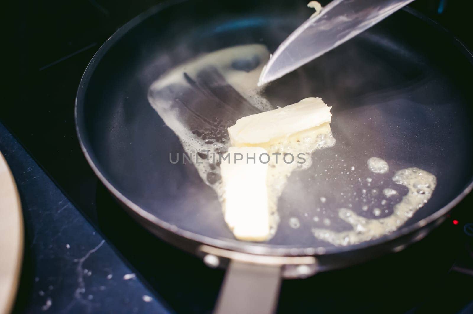 woman housewife prepares fried eggs with ham and vegetables in his kitchen. spreads the butter in the pan
