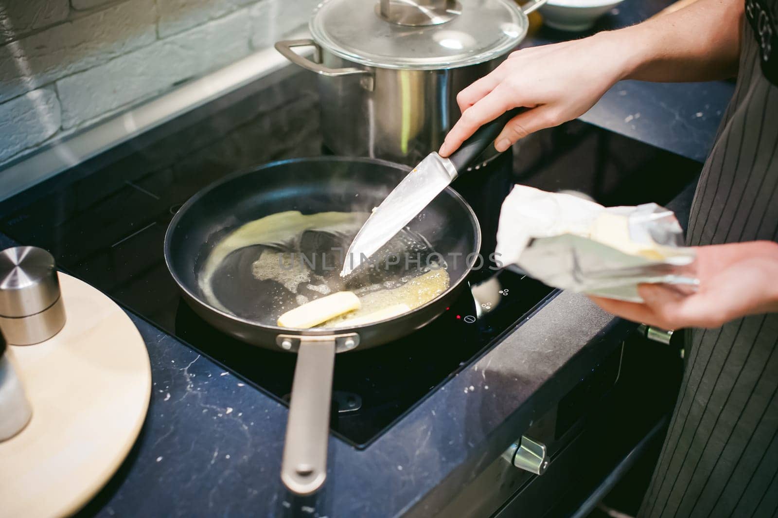 woman housewife prepares fried eggs with ham and vegetables in his kitchen. spreads the butter in the pan