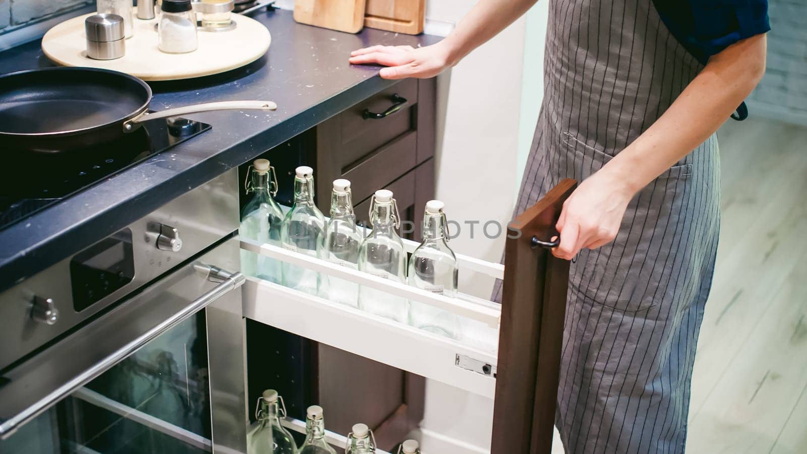 woman housewife in the kitchen. woman in an apron opened the shelf with empty bottles