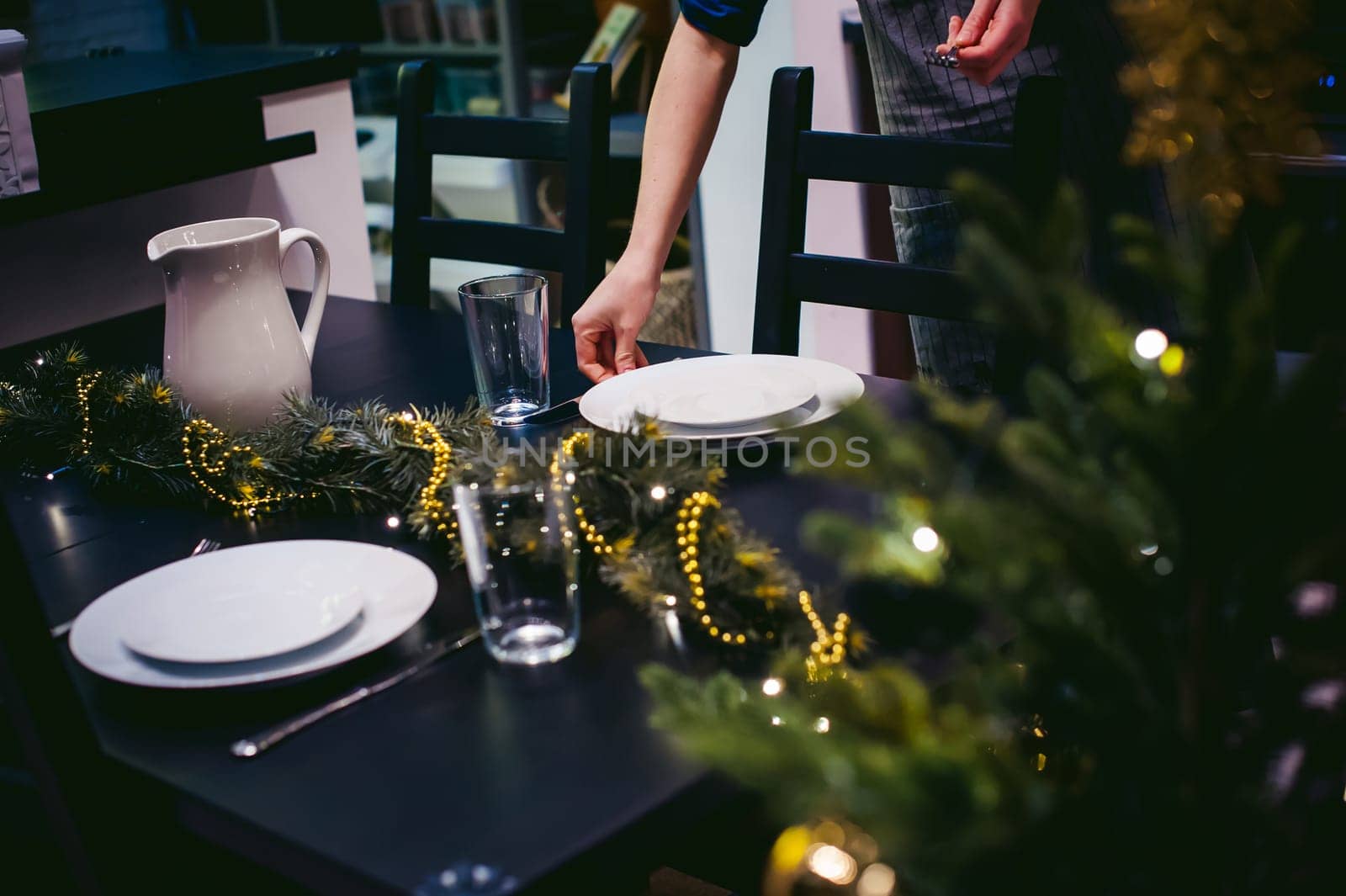 woman housewife setting the table. young blonde in a dress and apron, served in a dining table, puts the dishes, doing the work in the kitchen. lays out the forks and knives to persons
