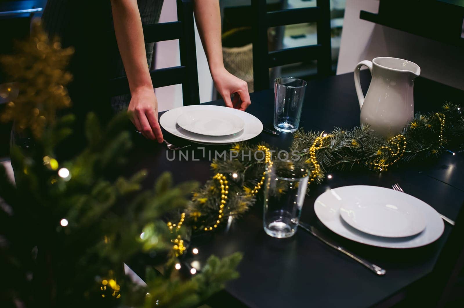 woman housewife setting the table. young blonde in a dress and apron, served in a dining table, puts the dishes, doing the work in the kitchen. lays out the forks and knives to persons