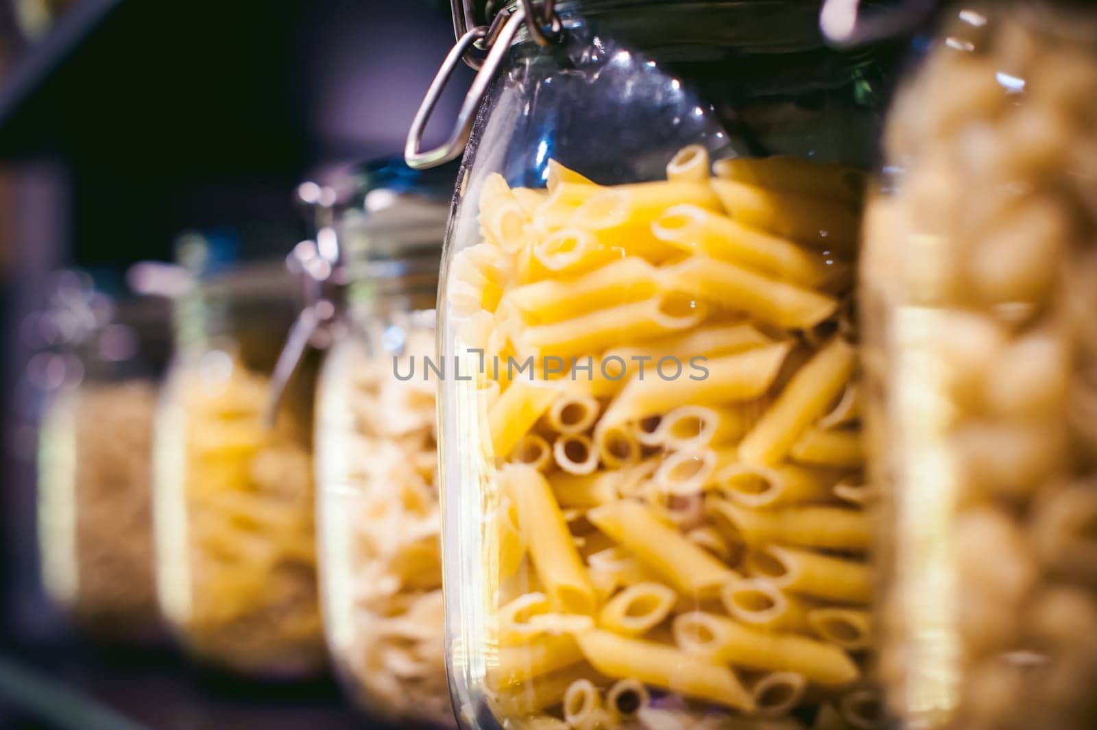 pasta in the jar. on kitchen shelves are different kinds of pasta in glass jars
