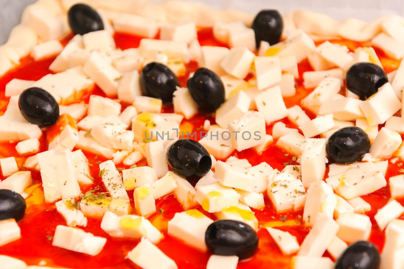 Raw pizza decorated mozzarella, black olives and tomato sauce ready to be baked