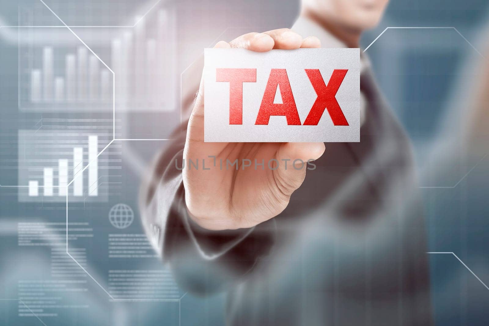 Businessman holding a card with Tax text over blue background