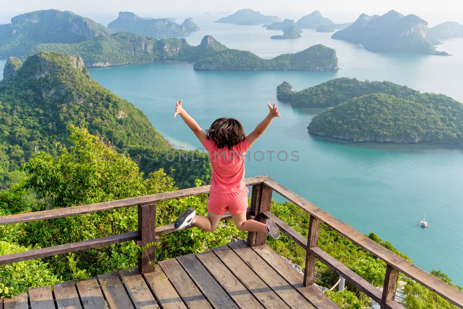 Woman tourist jumping with happy it has reached the peak mountain to see the beautiful natural landscape of sea from view point of Ko Wua Ta Lap island in Mu Ko Ang Thong, Surat Thani, Thailand
