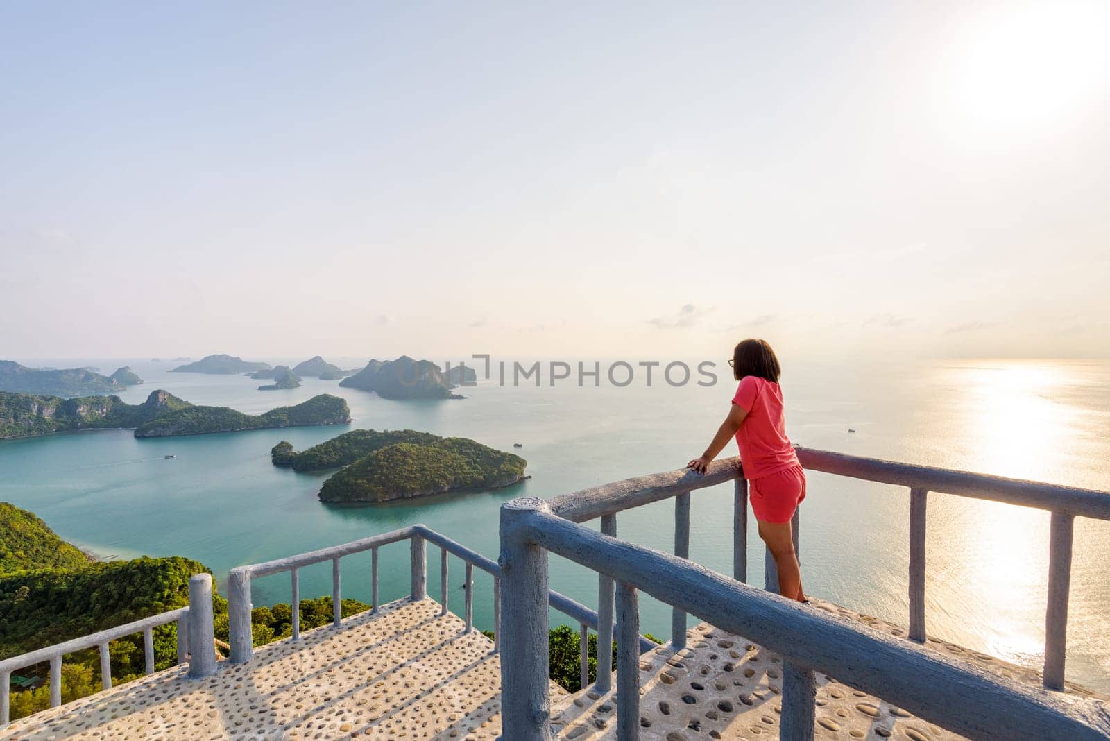Woman tourist on the podium is peak view point of Ko Wua Ta Lap island and beautiful nature landscape during sunrise over the sea in Mu Ko Ang Thong National Park, Surat Thani, Thailand