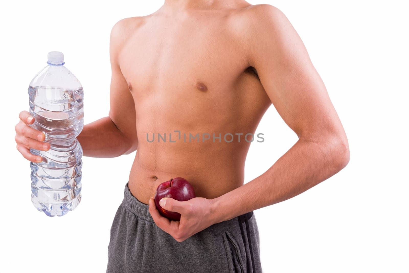 Young sporty man holding red apple and bottle of water. Sport or healthy life concept. White background with copy space.