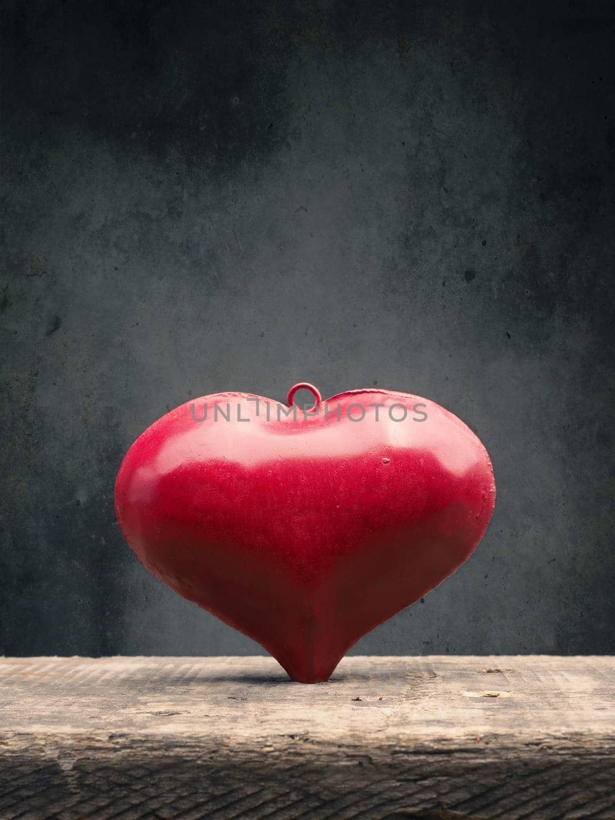 Close up of a red metal heart on a rustic wooden table with space for text, love or Valentines Day concept