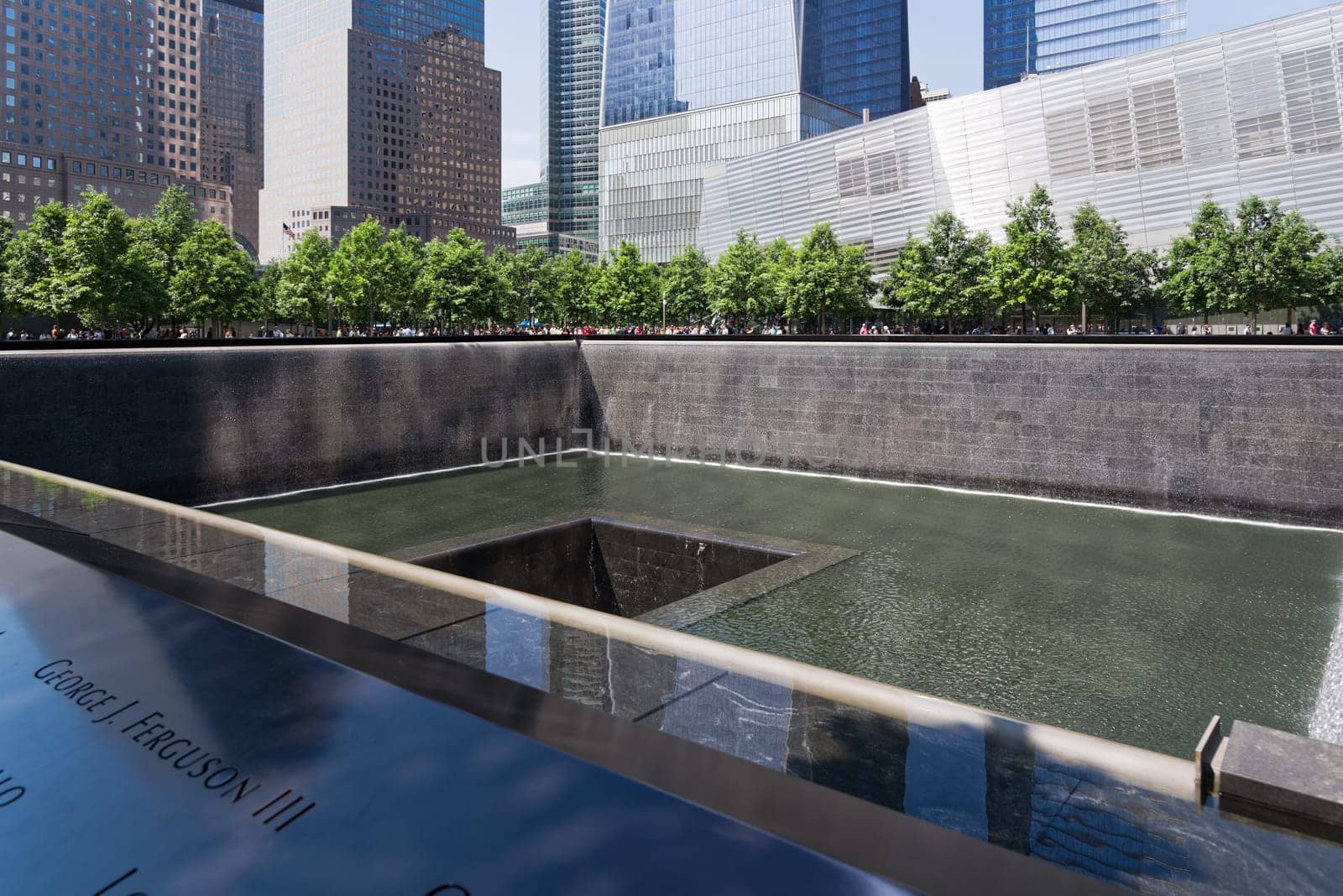New York, USA - June 08, 2015: South pool memorial commemorating the victims of the 11 september terror attack in 2001. New York architecture in the background.