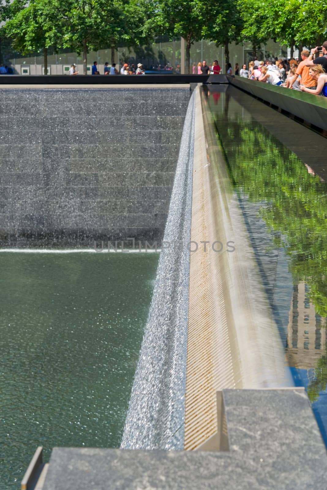 New York, USA - June 08, 2015: South pool memorial commemorating the victims of the 11 september terror attack in 2001. New York architecture in the background.