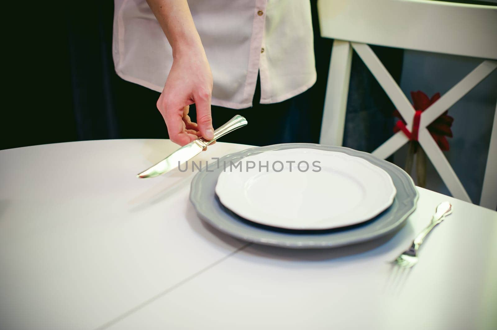 blonde woman housewife doing the work in the kitchen, setting the table, puts the dishes and cutlery. home in the kitchen in a bright interior