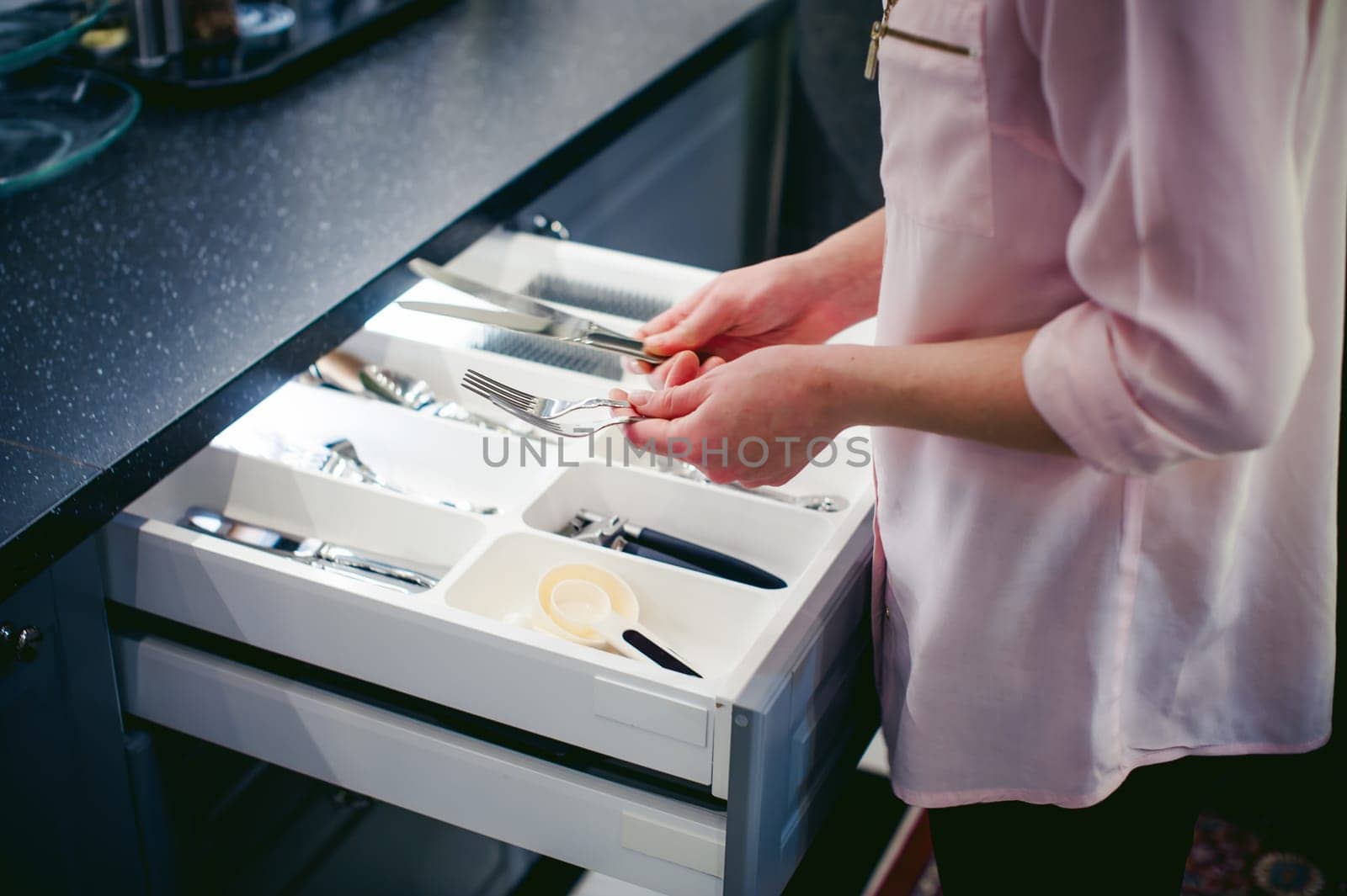 blonde woman housewife doing the work in the kitchen, setting the table, puts the dishes and cutlery. home in the kitchen in a bright interior