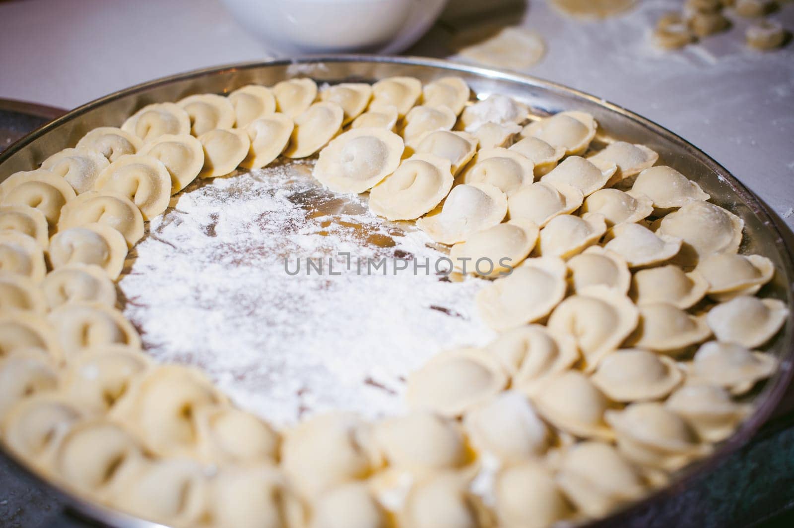 hand modeling dumplings at home in the kitchen. pelmeni lay on a baking sheet