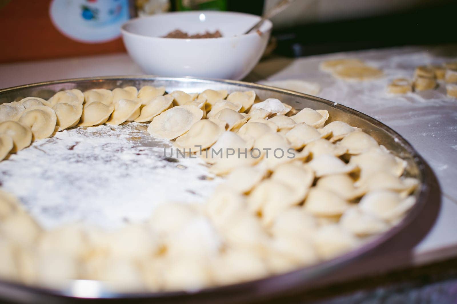 hand modeling dumplings at home in the kitchen. pelmeni lay on a baking sheet